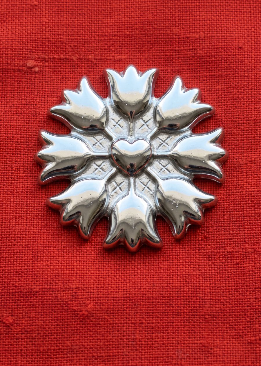 a chrome folk rosette of eight tulip petals radiating around a round heart