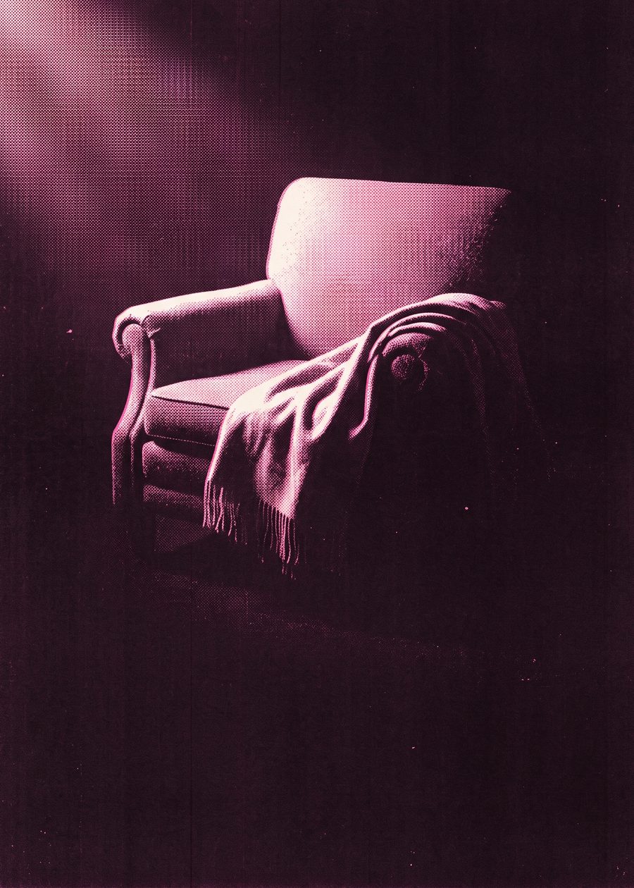 an empty armchair with a folded wool blanket draped over one arm